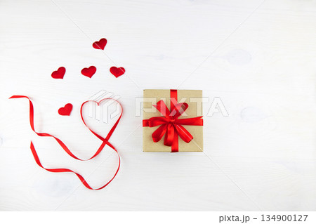 Gift box in craft paper packaging with red ribbon and heart-shaped ribbon 134900127