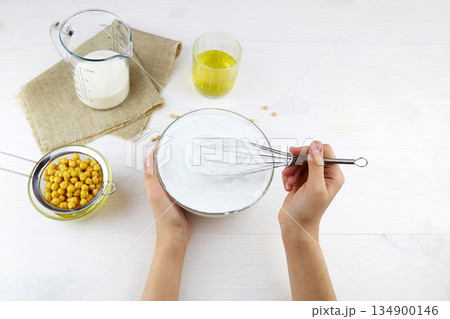Aquafaba. A womans hand whips the liquid from the boiled chickpeas with a whisk. 134900146