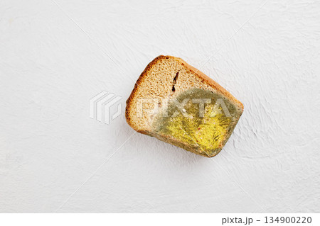 Moldy bread. Wasted, spoiled and moldy food on a gray background. 134900220