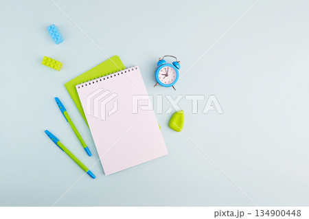 School supplies on light blue background. Notebook, pens, alarm clock 134900448