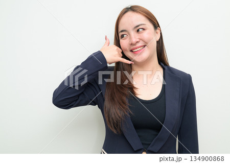 Portrait of a young Asian businesswoman against white background making call me phone hand gesture Portrait of a young Asian businesswoman against white background making call me phone hand gesture 134900868