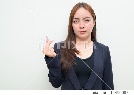 Portrait of a young Asian businesswoman against white background showing mini finger heart gesture Portrait of a young Asian businesswoman against white background showing mini finger heart gesture 134900873