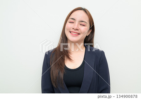 Portrait of a young Asian businesswoman against white background eyes closed smiling Portrait of a young Asian businesswoman against white background eyes closed smiling 134900878