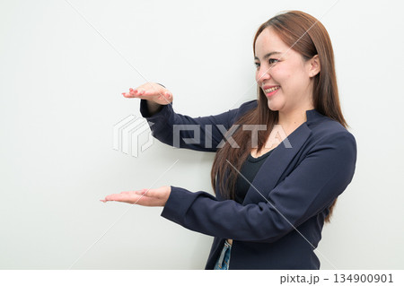Portrait of a young Asian businesswoman against white background measuring amount with hands 134900901