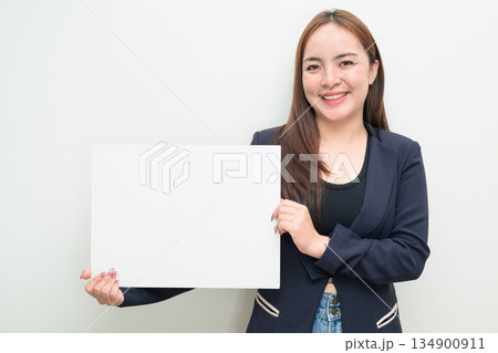 Portrait of young Asian businesswoman against white background showing copy space from white board Portrait of young Asian businesswoman against white background showing copy space from white board 134900911