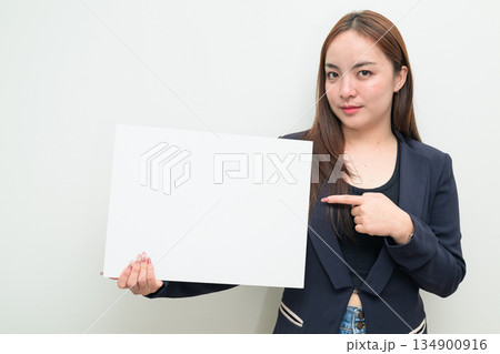 Portrait of young Asian businesswoman against white background showing copy space from white board Portrait of young Asian businesswoman against white background showing copy space from white board 134900916