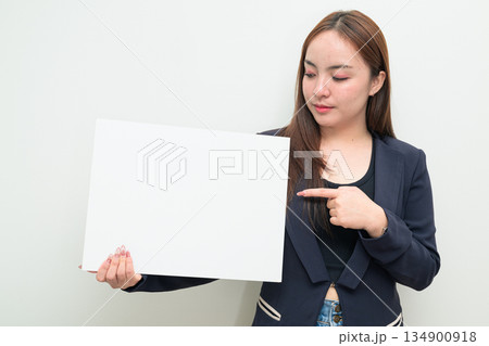Portrait of young Asian businesswoman against white background showing copy space from white board Portrait of young Asian businesswoman against white background showing copy space from white board 134900918