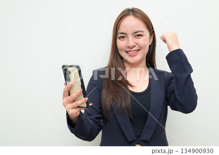 Portrait of a young happy Asian businesswoman against white background using phone smiling 134900930
