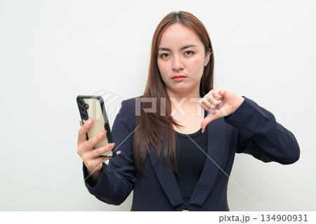Portrait of a young Asian businesswoman against white background using phone Portrait of a young Asian businesswoman against white background using phone 134900931