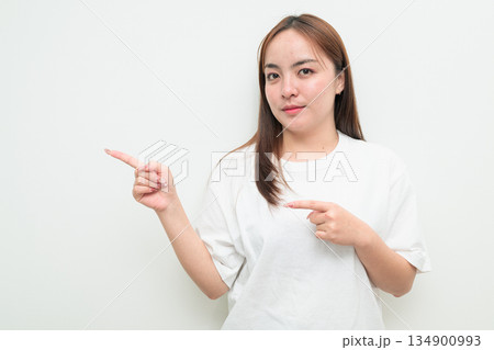 Portrait of a young Asian woman against white background pointing finger 134900993