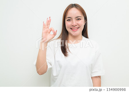 Happy young Asian woman against white background wearing t-shirt and smiling 134900998