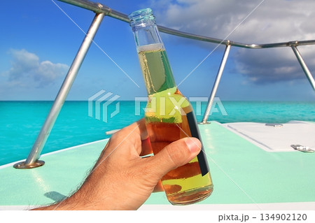 beer on hand Caribbean in boat bow turquoise sea 134902120