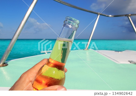 beer on hand Caribbean in boat bow turquoise sea beer on hand Caribbean in boat bow turquoise sea 134902642
