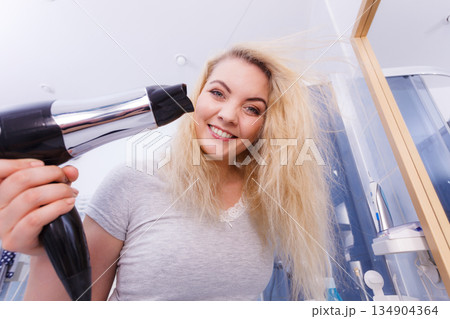 Woman drying hair in bathroom 134904364