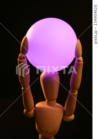 wooden mannequin holding  pink light ball on head 134904628