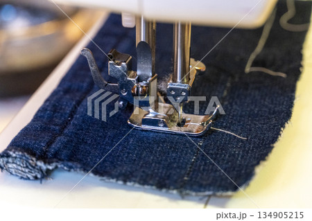 detail of a sewing machine needle on a piece of denim fabric detail of a sewing machine needle on a piece of denim fabric 134905215