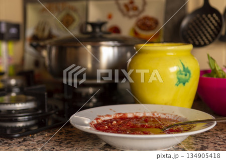 white dish with tomato and crushed garlic with kitchen utensils in the background 134905418