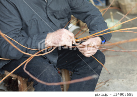 close-up of a wicker craftsman's hands preparing a basket close-up of a wicker craftsman's hands preparing a basket 134905689