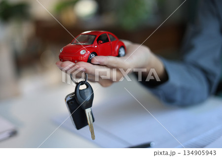 Car model and car key in hand. Concept for car loan, lease, insurance, buying or selling. Car model and car key in hand. Concept for car loan, lease, insurance, buying or selling. 134905943