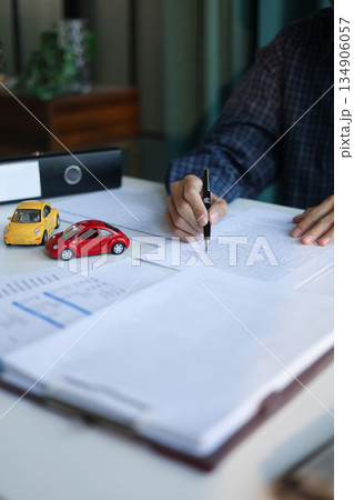 A man signing a contract for a car loan, lease, vehicle registration or insurance policy. Concept for Sales Contract, Financing Agreement, Insurance Policy, Vehicle Registration. A man signing a contract for a car loan, lease, vehicle registration or insurance policy. Concept for Sales Contract, Financing Agreement, Insurance Policy, Vehicle Registration. 134906057