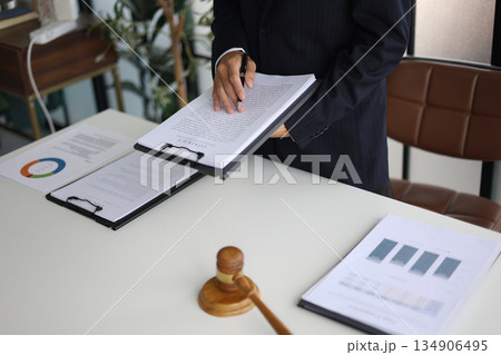 Legal counsel reading contract paperwork to finalize a legal agreement. Concepts for legal counsel, judicial authority, and the finality of a decision or agreement. 134906495