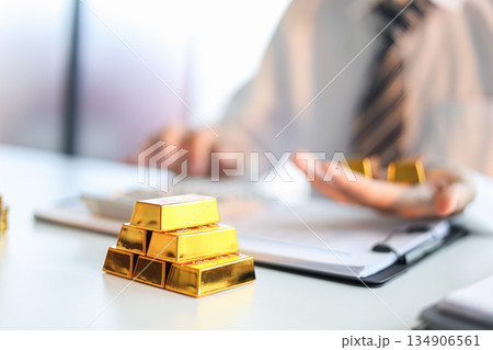 Gold bars on the table. Businessman invest in trading actual gold, calculating profit price of buy and sell gold. Gold bars on the table. Businessman invest in trading actual gold, calculating profit price of buy and sell gold. 134906561