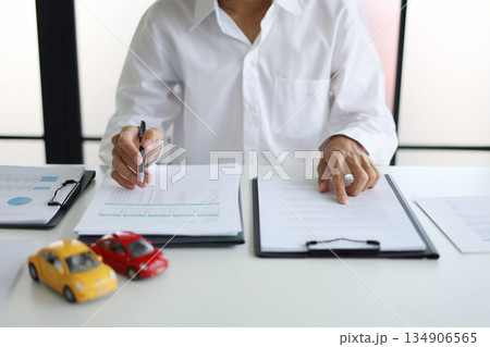 A man signing a contract for a car loan, lease, vehicle registration or insurance policy.Concept for Sales Contract, Financing Agreement, Insurance Policy, Vehicle Registration 134906565