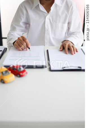 A man signing a contract for a car loan, lease, vehicle registration or insurance policy.Concept for Sales Contract, Financing Agreement, Insurance Policy, Vehicle Registration 134906566