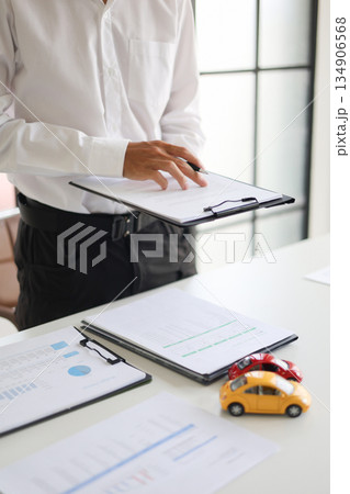 A man signing a contract for a car loan, lease, vehicle registration or insurance policy.Concept for Sales Contract, Financing Agreement, Insurance Policy, Vehicle Registration A man signing a contract for a car loan, lease, vehicle registration or insurance policy.Concept for Sales Contract, Financing Agreement, Insurance Policy, Vehicle Registration 134906568