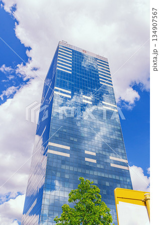 South Tower skyscraper modernism architecture style, modern high-rise office building, abstract details of facade glass curtain wall cells reflecting white clouds in blue sky, Brussels city, Belgium 134907567