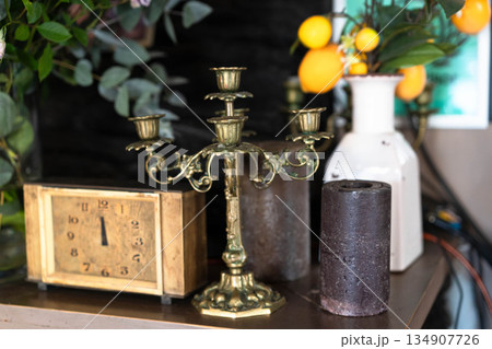 A beautifully arranged vintage display features an ornate candelabra, an antique clock, and floral accents. This charming setup invites family and friends to enjoy cozy dining moments together. A beautifully arranged vintage display features an ornate candelabra, an antique clock, and floral accents. This charming setup invites family and friends to enjoy cozy dining moments together. 134907726