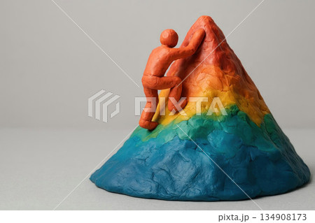 A man made of plasticine climbs a multi colored mountain. Space for text. A man made of plasticine climbs a multi colored mountain. Space for text. 134908173