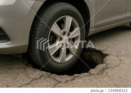 The wheel of the car got stuck in a deep hole in the road. 134908322