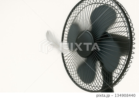 A black table fan picks up a light pen. Space for text. A black table fan picks up a light pen. Space for text. 134908440