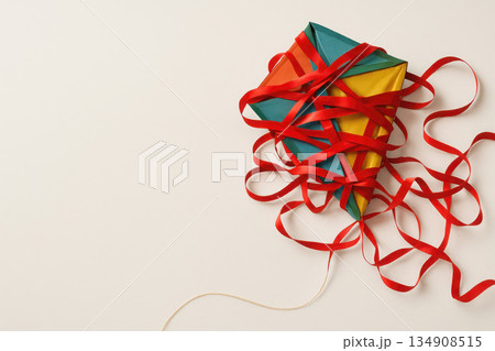 A multi-colored kite entangled in red ribbons. Space for text. 134908515