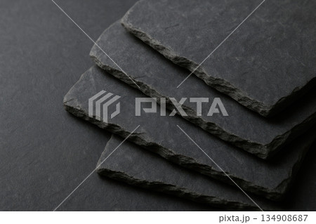 Black stone slabs lying in layers on a dark background. 134908687