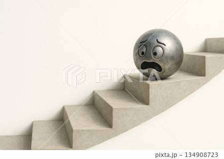 A metal ball with a face of fear rolling down the stairs. Space for text. 134908723