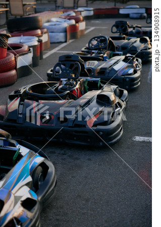 Go-karting track featuring parked karts lined up along a red and white tire barrier 134908915