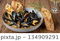 Seafood dish of mussels, bread, and wine on wooden table 134909291