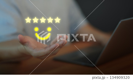 Customer satisfaction concept with five star rating and smile face above hand, symbolizing positive feedback, quality service, online reviews, testimonial, and excellent user experience. 134909320