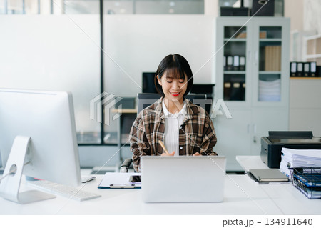Business woman using tablet and laptop for doing math finance on an office desk, tax, report, accounting, statistics, and analytical research concept in office Business woman using tablet and laptop for doing math finance on an office desk, tax, report, accounting, statistics, and analytical research concept in office 134911640