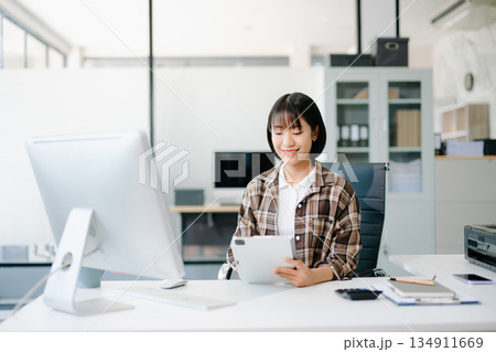 Beautiful Asian business woman typing laptop and tablet Placed at the table at the office Beautiful Asian business woman typing laptop and tablet Placed at the table at the office 134911669