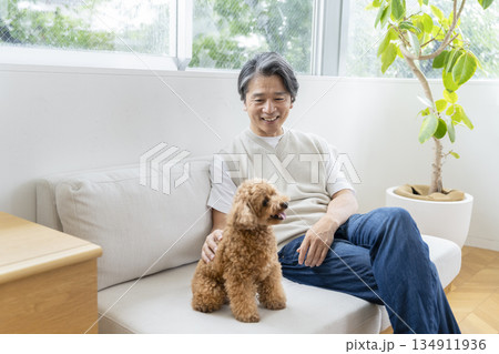 ソファでくつろぐ50代の男性と犬　犬との暮らしイメージ 134911936