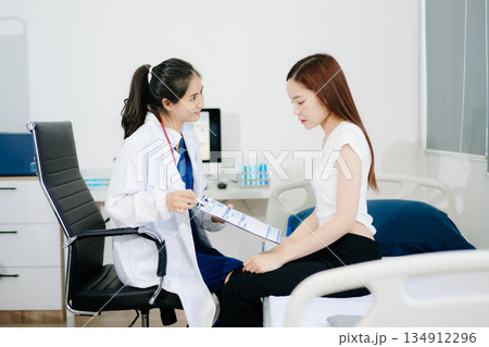 Asian female doctor explains diagnosis with compassion during a medical consultation. Perfect for healthcare, trust, patient care 134912296