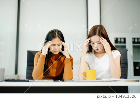 Asian woman comforts her distressed coworker in office. Concept of workplace stress, burnout, empathy, and emotional support in professional environments. Asian woman comforts her distressed coworker in office. Concept of workplace stress, burnout, empathy, and emotional support in professional environments. 134912326