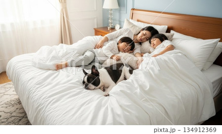 朝の光の中で一緒に眠る両親と子供たちとペットの犬 134912369