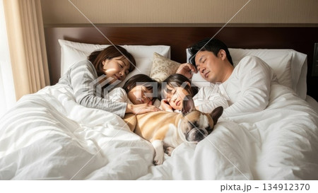 朝の光の中で一緒に眠る両親と子供たちとペットの犬 134912370