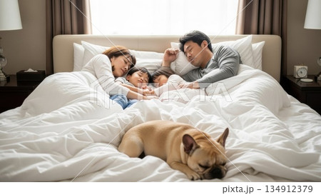 朝の光の中で一緒に眠る両親と子供たちとペットの犬 134912379