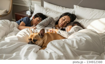 朝の光の中で一緒に眠る両親と子供たちとペットの犬 134912380