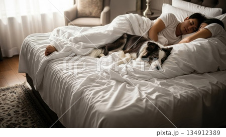 朝の光の中で犬と添い寝する若いカップルの穏やかな寝顔 134912389
